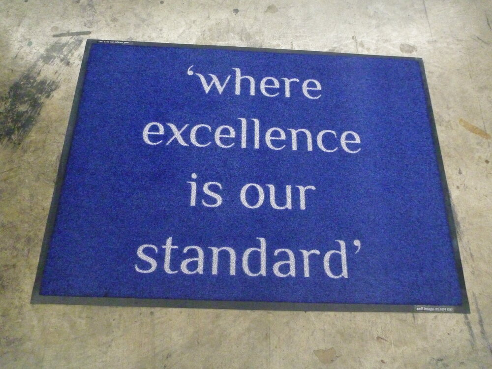 Blue doormat reading Where excellence is our standard